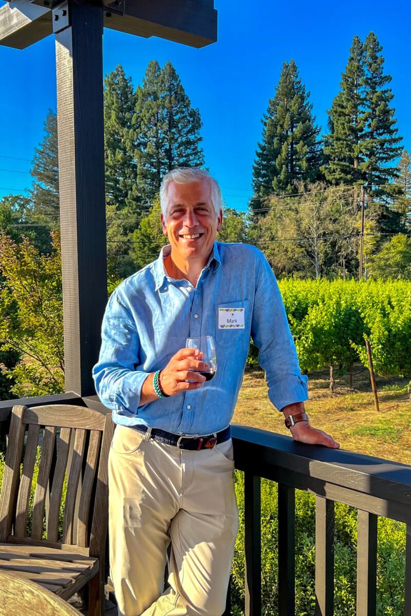 Mark Orsi standing by vineyard holding glass of wine